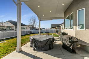 Fenced backyard featuring a patio, grilling area, and a residential view