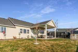 Back of property featuring a patio, a yard, a shingled roof, and stucco siding