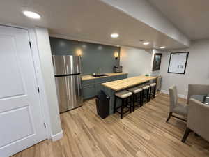 Kitchen with freestanding refrigerator, butcher block countertops, a breakfast bar area, a peninsula, and a textured ceiling