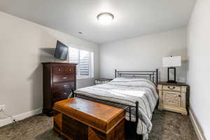 Bedroom with baseboards and dark colored carpet