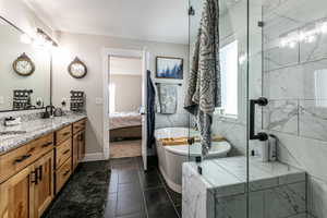 Ensuite bathroom with a soaking tub, double vanity, dark tile patterned flooring, and a marble finish shower