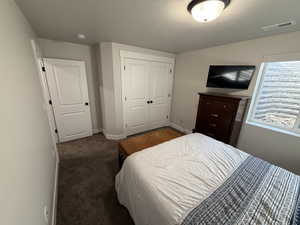 Carpeted bedroom with a textured ceiling and a closet