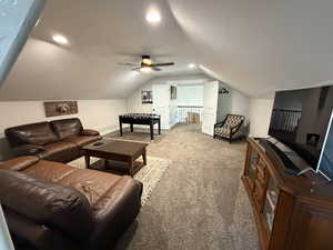 Carpeted living area with ceiling fan, vaulted ceiling, and recessed lighting