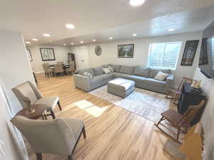 Living room featuring recessed lighting, light wood finished floors, and a textured ceiling