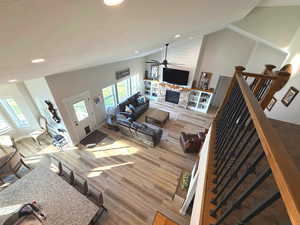 Living room featuring high vaulted ceiling, light wood-type flooring, recessed lighting, and a stone fireplace