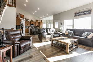 Living room with recessed lighting, high vaulted ceiling, light wood finished floors, and stairway