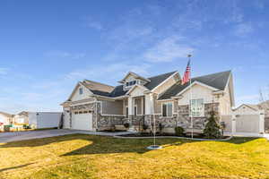 Craftsman house featuring board and batten siding, stone siding, a shingled roof, and concrete driveway