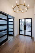 Entrance foyer featuring french doors, light wood finished floors, and a chandelier