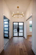Entryway with french doors, hardwood / wood-style flooring, plenty of natural light, and a chandelier