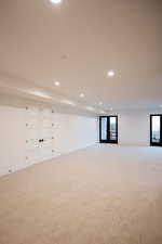 Basement with recessed lighting, light carpet, and french doors