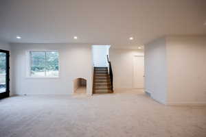Basement featuring light carpet, recessed lighting, and stairs