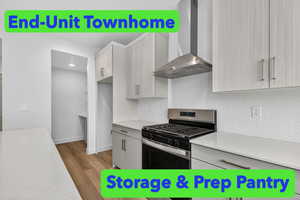 Kitchen featuring stainless steel gas stove, wall chimney range hood, light stone counters, modern cabinets, and backsplash