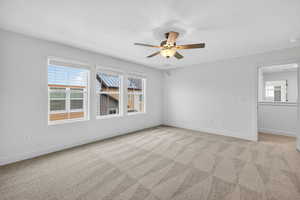 Empty room featuring plenty of natural light, light carpet, and a ceiling fan