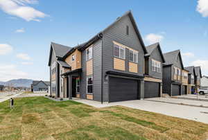 View of side of property with a residential view, a lawn, a garage, and concrete driveway