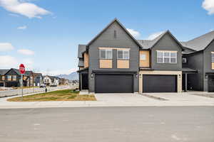 View of front of property featuring a residential view, concrete driveway, an attached garage, a standing seam roof, and a metal roof