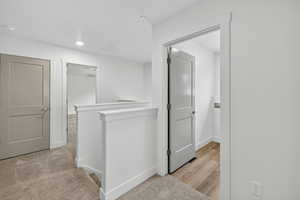 Hallway with light carpet and baseboards