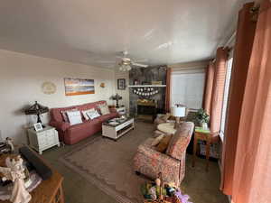 Carpeted living area featuring a textured ceiling, a fireplace, and ceiling fan