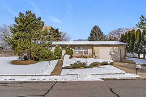View of front of house with a garage, a balcony, concrete driveway, a mountain view, and brick siding