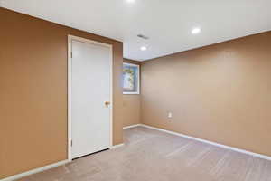 Unfurnished room featuring a textured wall, light colored carpet, and recessed lighting