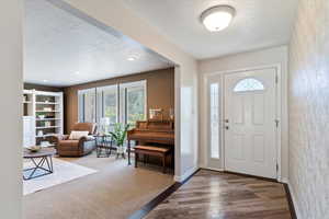Entryway with a textured ceiling, healthy amount of natural light, wood finished floors, and carpet floors