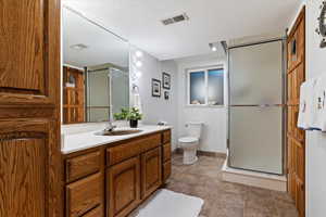 Bathroom featuring vanity, a shower stall, and a textured ceiling