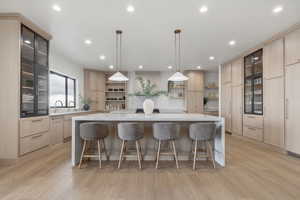 Kitchen with glass fronted cabinets, light stone countertops, a spacious island, and hanging light fixtures