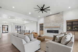 Living room with a fireplace, wood finished floors, recessed lighting, and ceiling fan