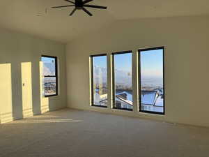 Empty room with light colored carpet, lofted ceiling, a ceiling fan, and a mountain view