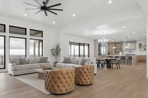 Living area with light wood-style floors, ceiling fan, and hanging lights