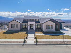 View of front of property featuring a mountain view, roof with shingles, and a front yard