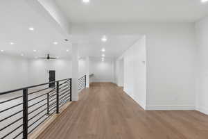 Hallway with an upstairs landing, recessed lighting, and light wood-style flooring