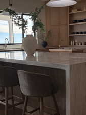 Bar featuring light stone countertops, wood finish cabinetry, and open shelves
