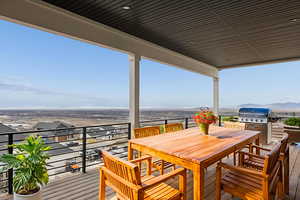 Wooden terrace with outdoor dining area, area for grilling, and a mountain view