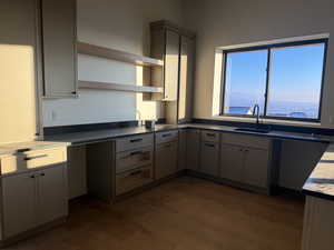 Kitchen featuring open shelves, gray cabinetry, dark wood finished floors, and dark countertops