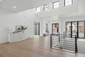 Foyer featuring hanging lights, light wood-style floors, and a high ceiling