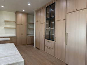 Kitchen featuring recessed lighting, light brown cabinets, open shelves, light wood-style flooring, and glass insert cabinets