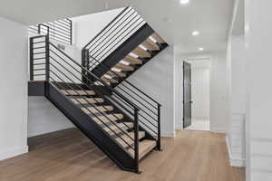 Stairway featuring wood finished floors and recessed lighting