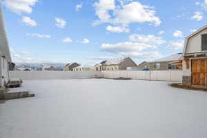 Yard covered in snow with a fenced backyard and a residential view