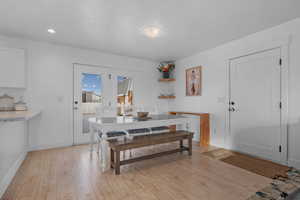 Dining area with light wood finished floors and recessed lighting