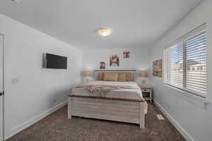 Bedroom with dark colored carpet and baseboards