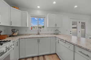 Kitchen with white appliances, white cabinets, recessed lighting, and light wood-style flooring
