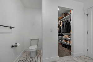 Half bathroom featuring light marble finish floors and a spacious closet