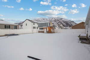 Snowy yard with a fenced backyard and a mountain view