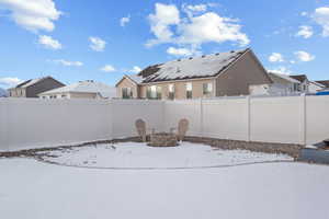 Snowy yard with a fire pit and a fenced backyard