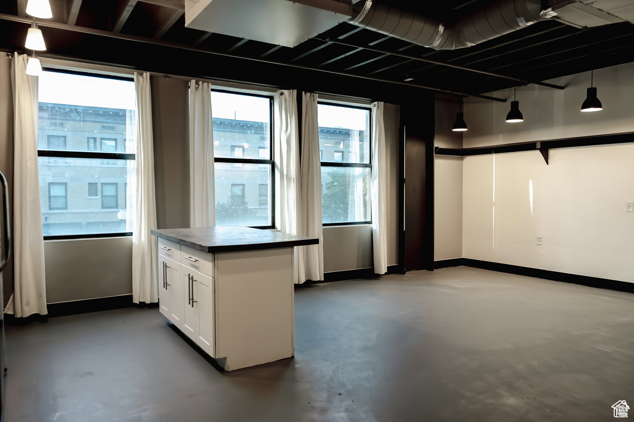 Kitchen featuring white cabinets, finished concrete floors, and dark countertops