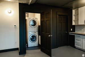 Washroom with stacked washer / dryer and finished concrete flooring