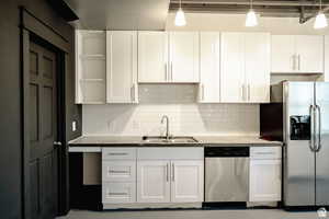 Kitchen with open shelves, white cabinets, appliances with stainless steel finishes, tasteful backsplash, and dark countertops