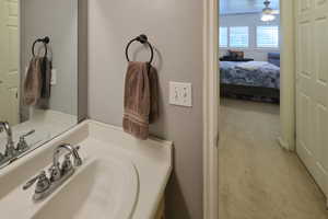 Ensuite bathroom featuring vanity, carpet floors, and ceiling fan
