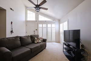 Carpeted living area with a ceiling fan and high vaulted ceiling