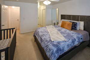 Bedroom featuring light carpet, a ceiling fan, and a closet
